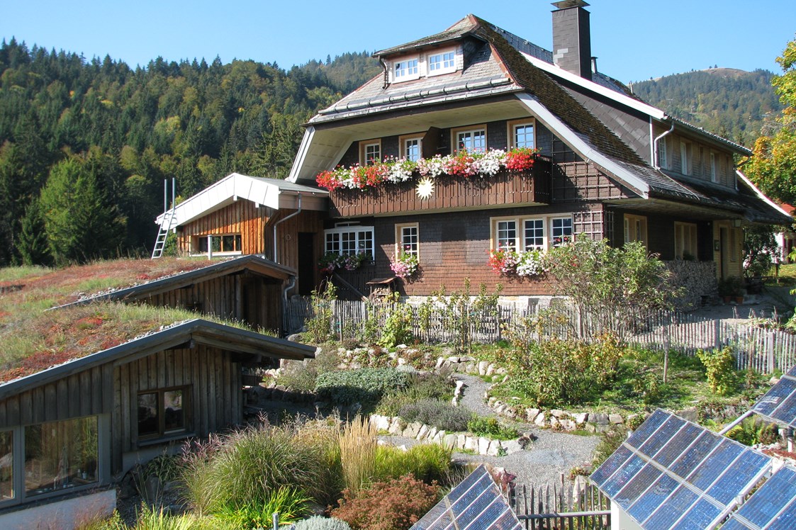 Biohotel: Haus Sonne im Sommer, im Vordergrund der Kräutergarten und Solarpanels. - Haus Sonne - das vegetarische Bio-Hotel