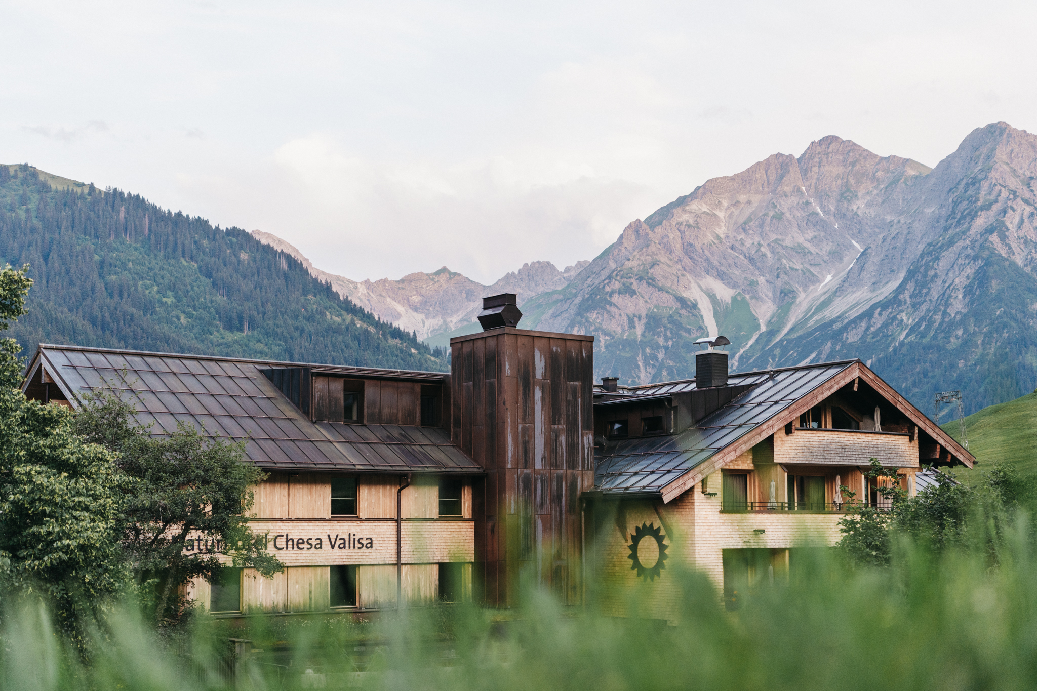 Naturhotel - Bio-Küche: Saisonale Speisen - Bodensee - Bregenzer Wald - Rückseite Stammhaus mit Berge im Hintergrund - Das Naturhotel Chesa Valisa****s